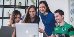 vier personen, die vor einem Laptop sitzen und sprechen